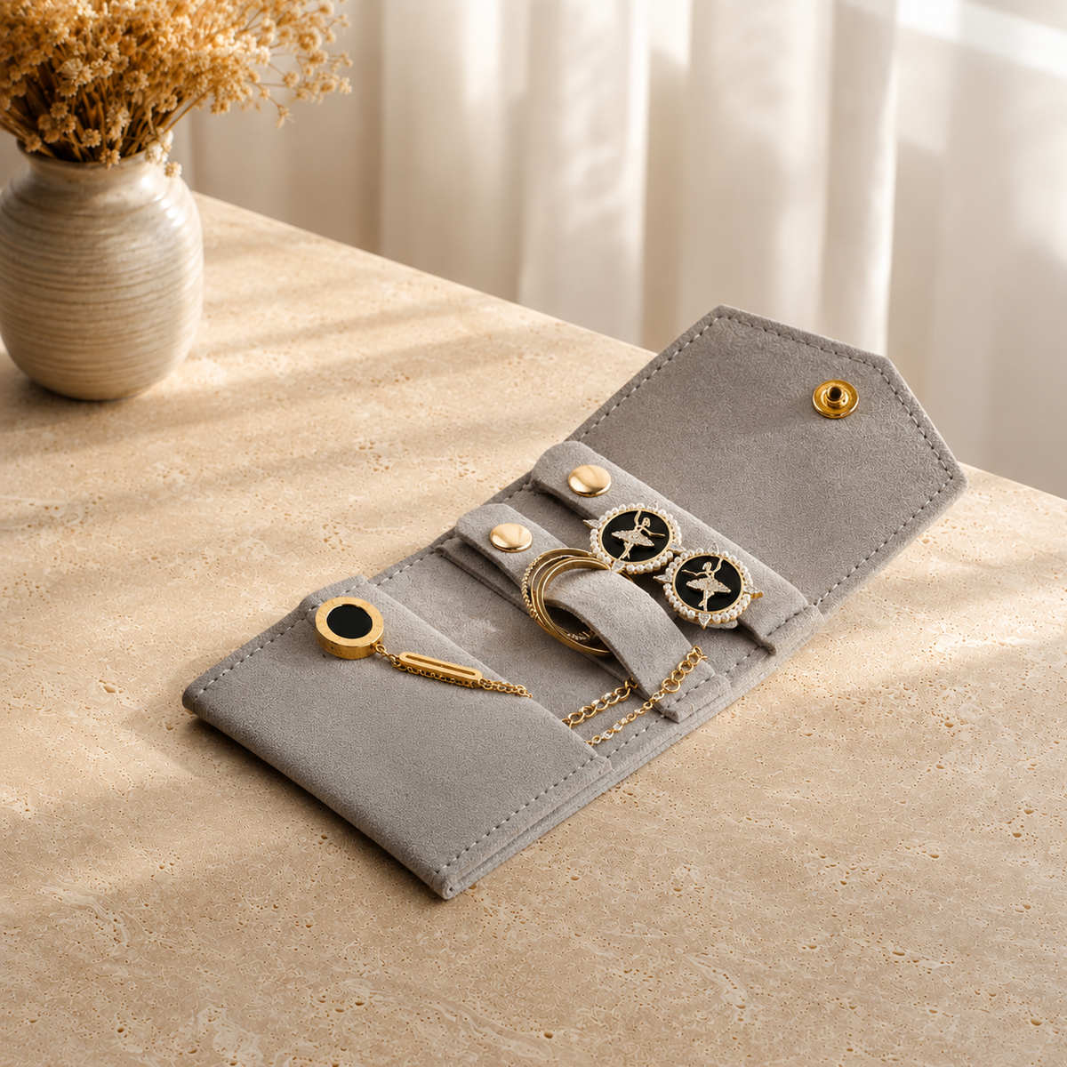 Pochette Bijoux Voyage Suédine presente en situation (Gris) avec vase de fleurs sechees en arriere-plan