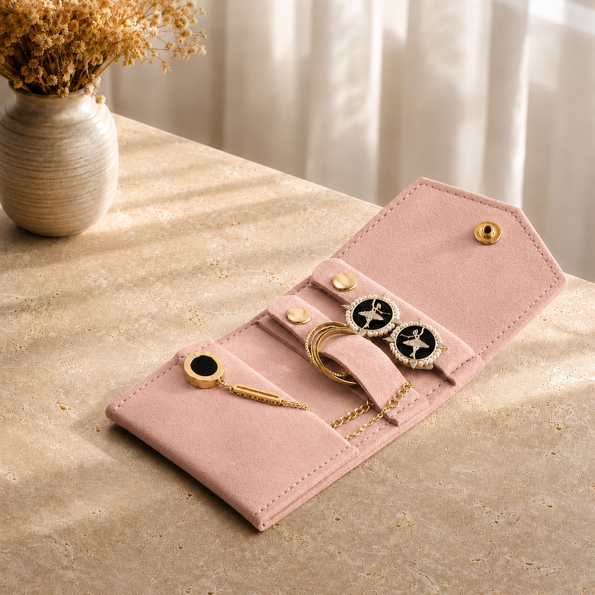 Pochette Bijoux Voyage Suédine presente en situation (Rose) avec vase de fleurs sechees en arriere-plan